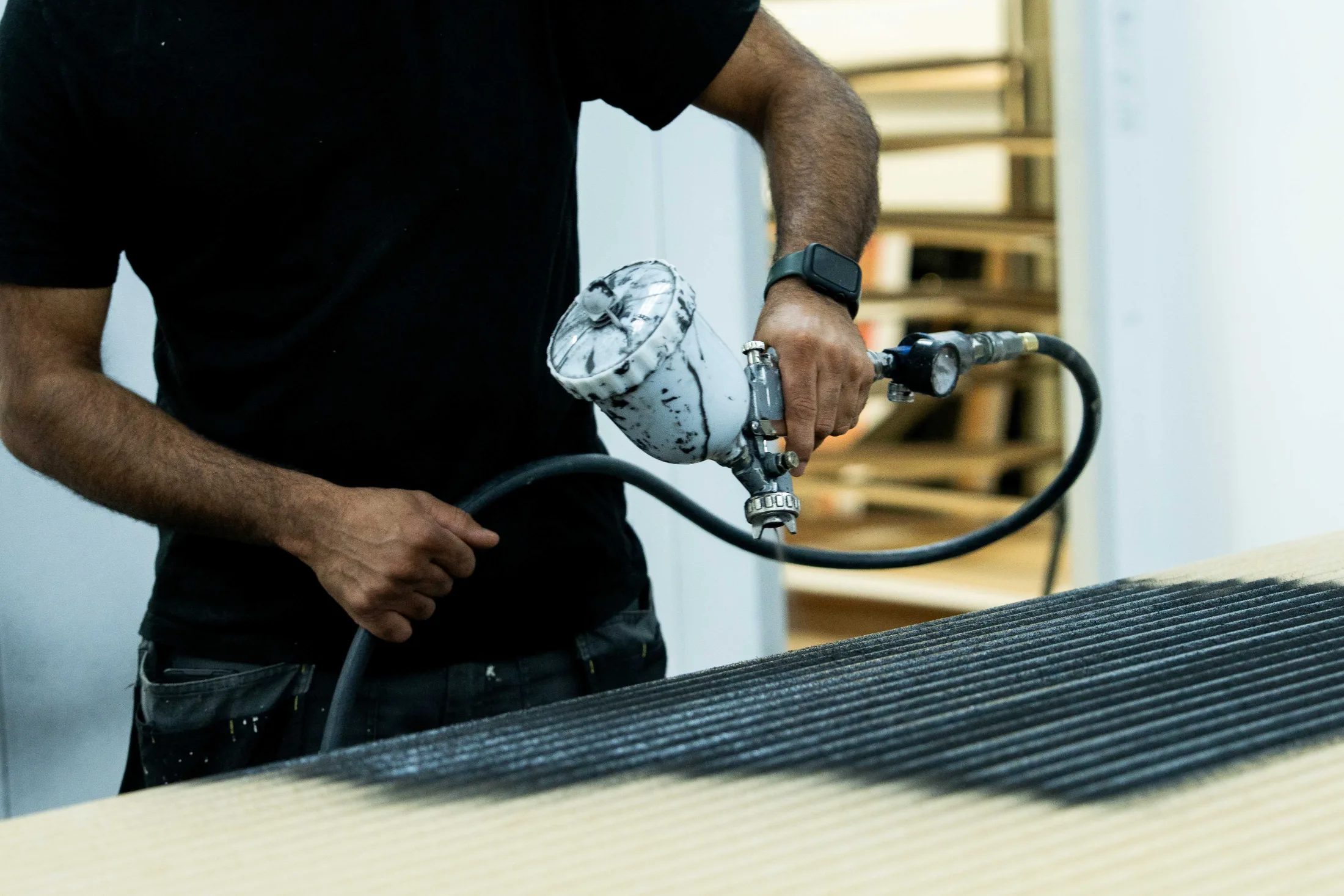 Spraying a panel in a satin black finish inside the booth